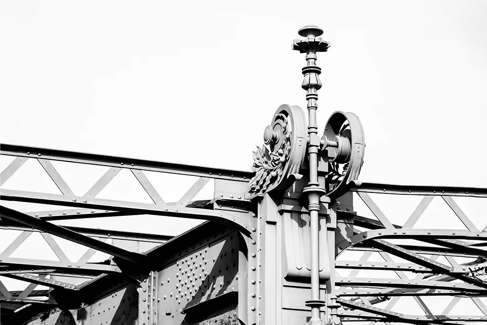 Black and white image of steel construction detail with flowery ornaments of the bridge crossing the intake of the Danube Canal in Vienna.
